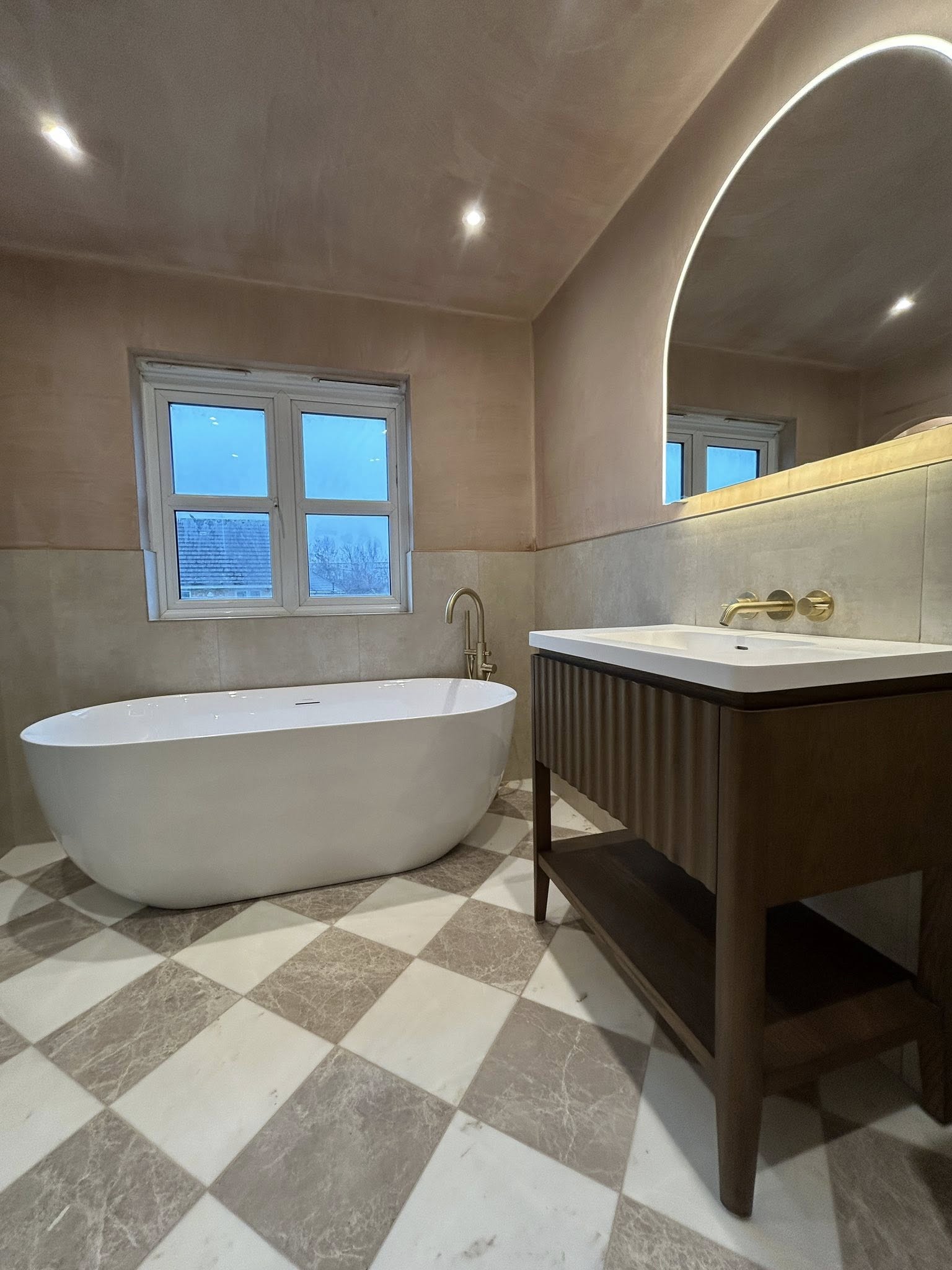 Freestanding bath with brushed brass taps and chequerboard marble floor
