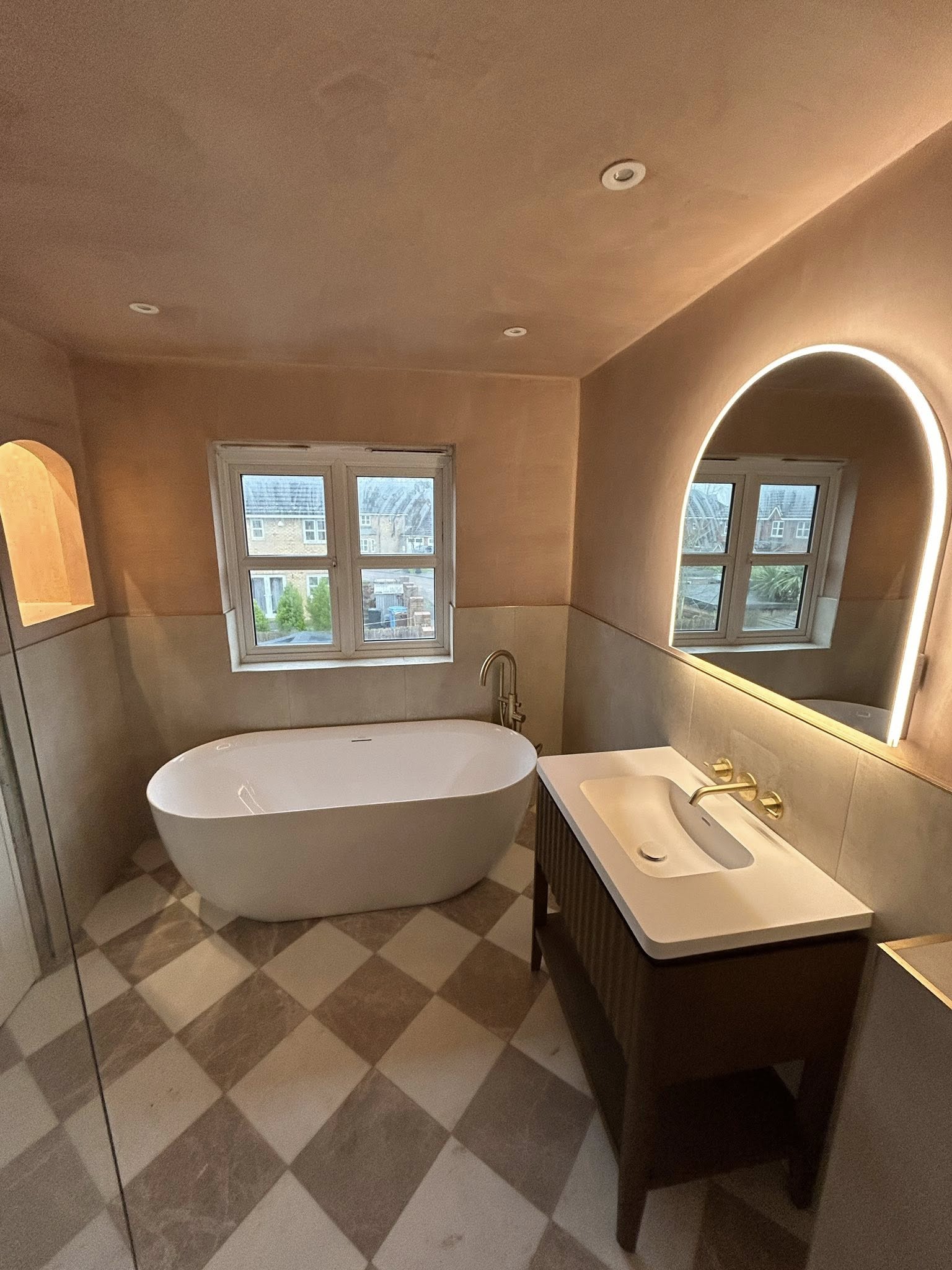 Freestanding bath with arch mirror and Venetian plaster