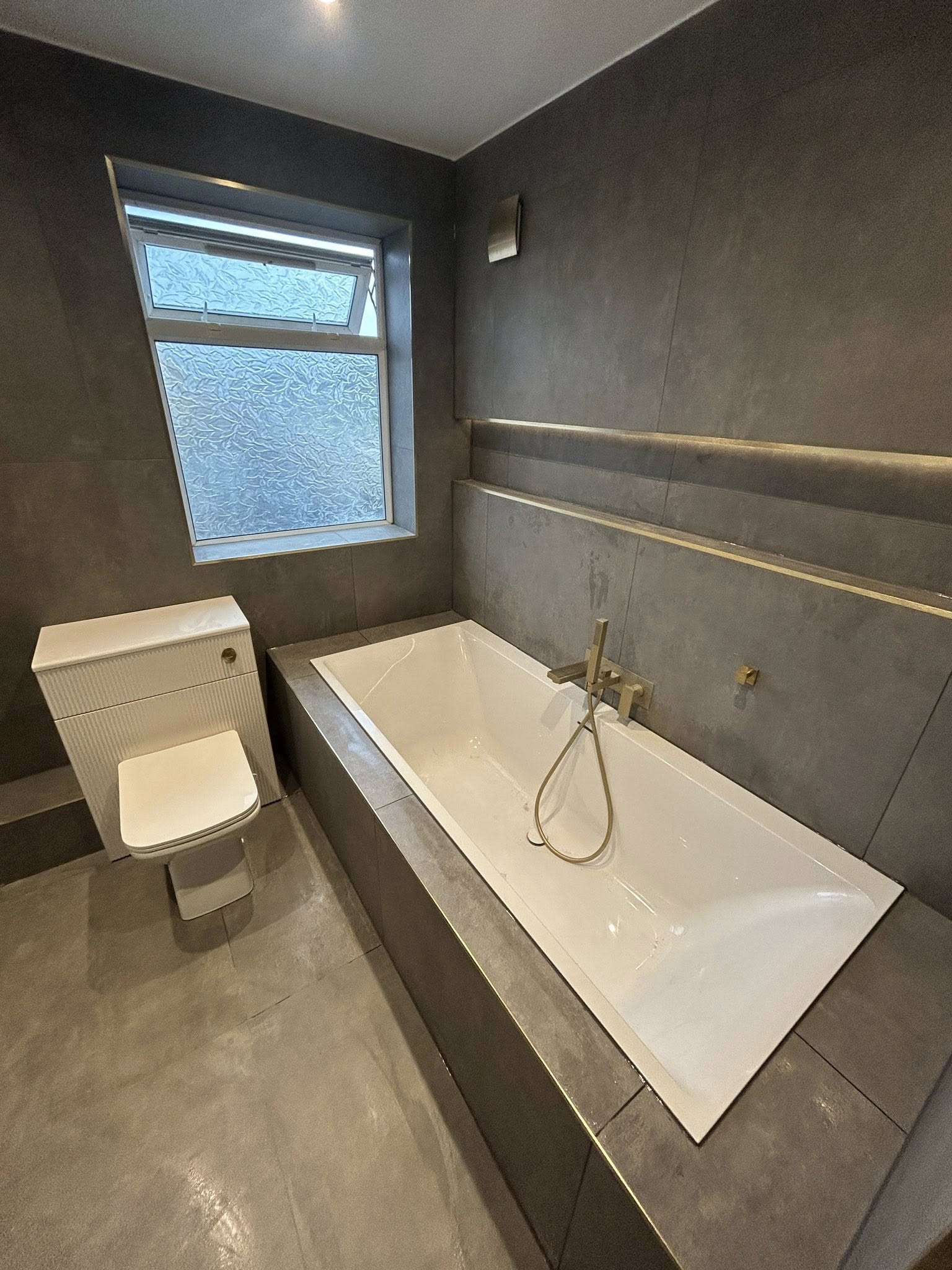 Grey stone bathroom with LED niche and gold tapware